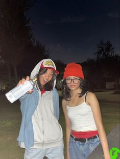 two young women standing next to each other in front of a skateboard ramp at night