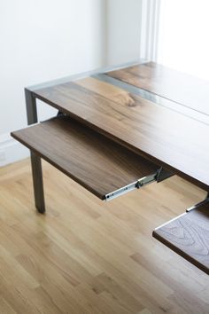 a wooden desk with metal legs and a laptop on it's side, in front of a window