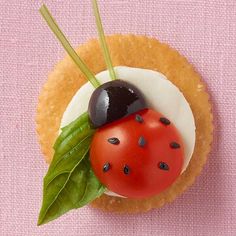 a cupcake decorated with a ladybug and cherry on top, sitting on a pink surface