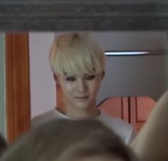 a person with blonde hair is looking in the mirror