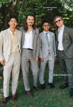 three men in suits and sunglasses standing next to each other on the grass with trees behind them