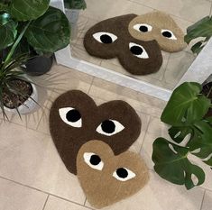 two brown and white rugs with eyes on them next to a potted plant