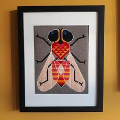 a cross - stitch picture of a fly with glasses on it's head and legs