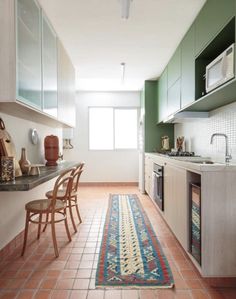 a kitchen with green walls and tile flooring next to a counter top oven, microwave and sink