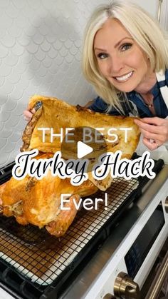 a woman holding up a large piece of chicken on top of a grill in front of an oven