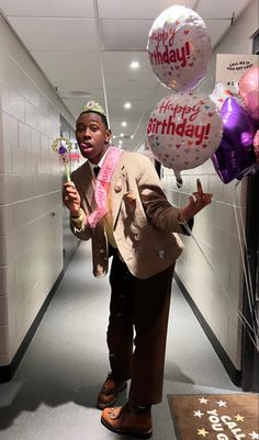 a man in a suit and tie holding balloons with the words happy birthday on them