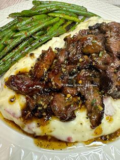 a white plate topped with meat covered in gravy and asparagus spears