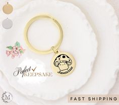 a gold keychain with the words perfect keepsake next to it on a white plate