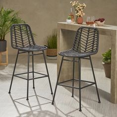 two chairs sitting next to each other in front of a table with potted plants