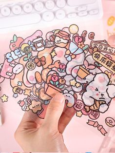 a hand holding up a sticker with various cartoon characters on it and the words hello kitty written in japanese