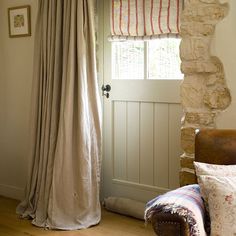 a living room with a couch, chair and window covered in draping next to a stone wall