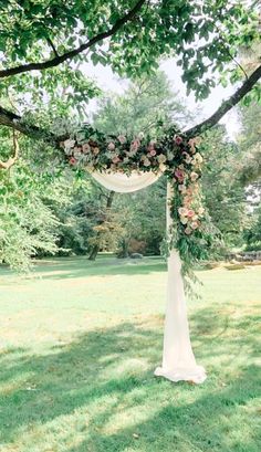 a wedding arch with flowers and greenery on it in the middle of a field