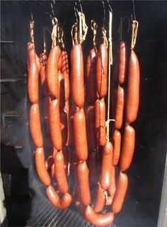 several sausages hanging from hooks on a grill