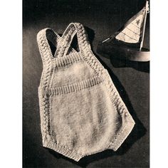 an old knitted baby's overall and sailboat on the table next to it