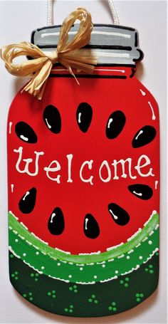 a painted welcome sign with a watermelon jar on it's front and bottom