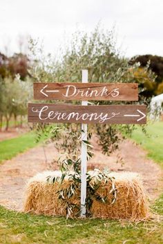 a wooden sign sitting on top of a hay bale in front of a field