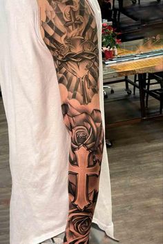 a man's arm with a cross and roses tattoo on the side of it