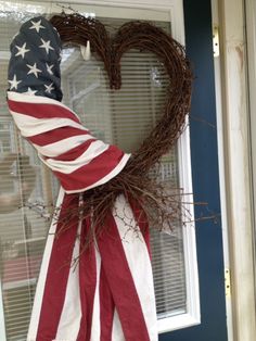 an american flag wreath hanging on the front door with a heart made out of branches