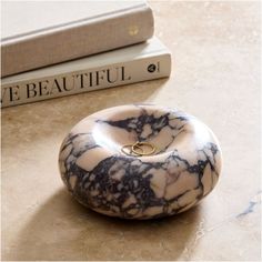 a marble ring holder sitting on top of a table next to two bookends