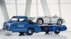 two classic cars on the back of a tow truck