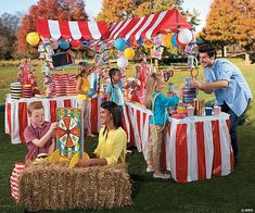 a group of people standing around a table with balloons and decorations on top of it