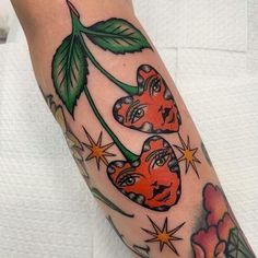 a woman's arm with tattoos on it and two hearts in the shape of flowers