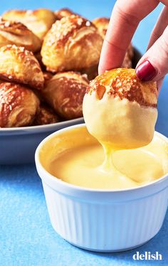 a person dipping something into a bowl of food with croissants in the background