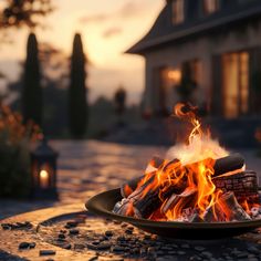 a fire pit sitting on top of a stone patio next to a house at sunset