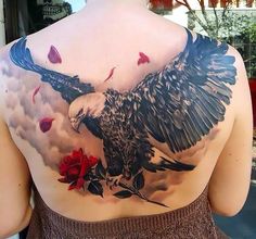 the back of a woman's shoulder with an eagle and roses on it