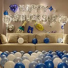 a couch with balloons and confetti on it in front of a happy anniversary sign