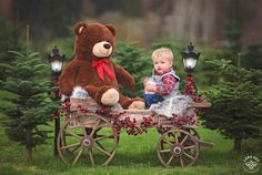 a baby sitting in a wagon with a teddy bear