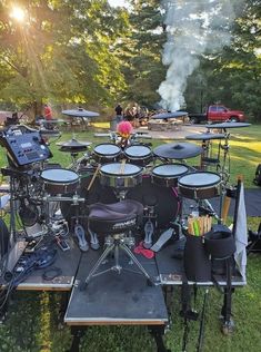 a group of musical instruments sitting on top of a lush green field next to trees