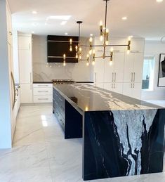 a large kitchen with marble counter tops and white cabinets in the background is an open floor plan