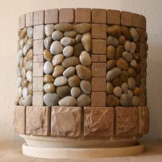 a vase made out of rocks sitting on top of a wooden table next to a wall