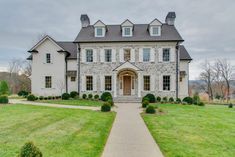 a large white house sitting on top of a lush green field