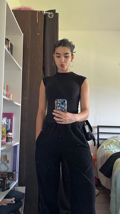 a woman standing next to a book shelf holding a cell phone