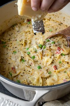 a person is scooping some food out of a pot with a spatula and cheese on top