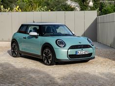 a small blue car parked in front of a fence