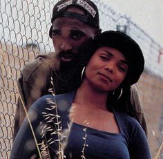 a man standing next to a woman near a fence