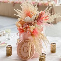 a pink vase filled with lots of flowers on top of a table next to candles