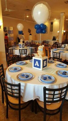 a table is set with blue and white plates, silverware, and balloons in the background