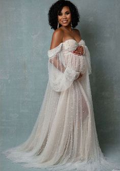 a pregnant woman in a white gown posing for the camera with her hands on her belly