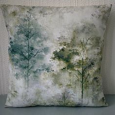 a pillow that is sitting on a table next to a white wall with trees painted on it