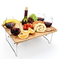 a wooden tray with wine, bread and fruit on it