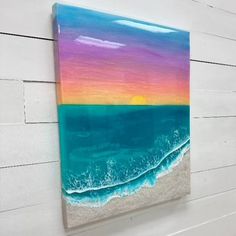 an acrylic painting of a sunset over the ocean on a white brick wall