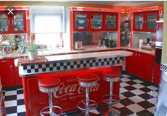 a kitchen with red cabinets and black and white checkered flooring