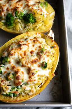 two stuffed squash halves with cheese and broccoli on the side, sitting on a baking sheet