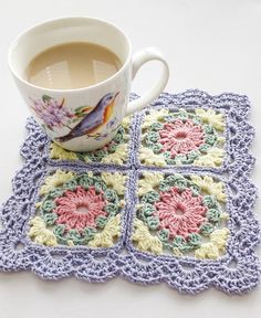 a cup of coffee sitting on top of a table next to a crocheted coaster