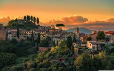 the sun is setting over an old town on top of a hill with trees in front of it