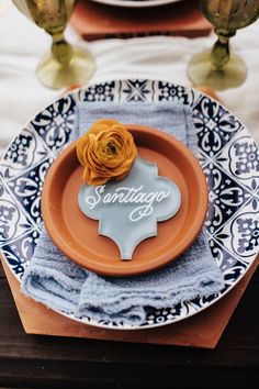 an orange flower is sitting on top of a blue and white plate that says saratoga